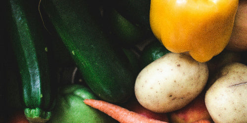 Assorted organic fresh vegetables including carrots, bell peppers, and potatoes 